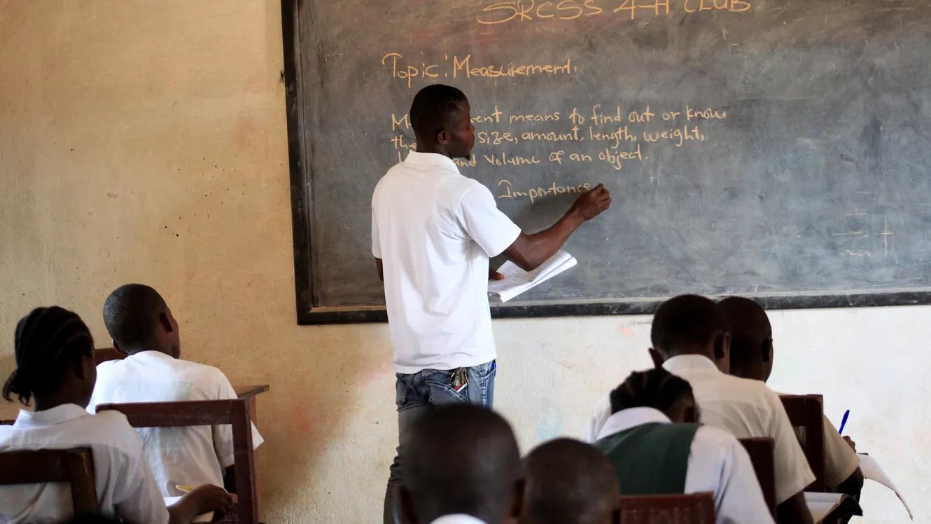 Teacher writing on a board in front of pupils