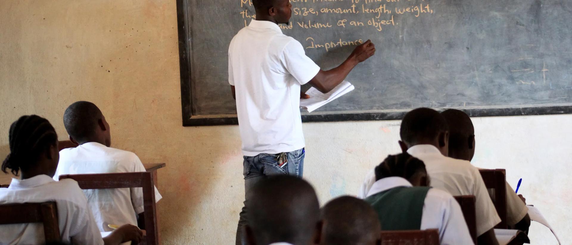 Teacher writing on a board in front of pupils