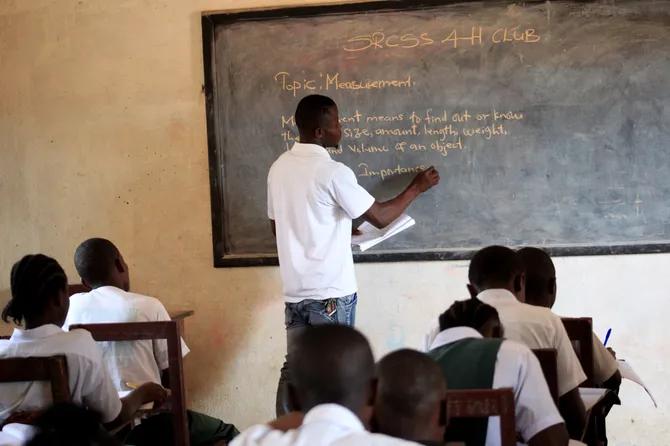 Teacher writing on a board in front of pupils